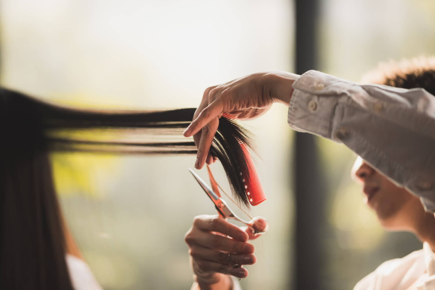 長い髪の女性の髪をカットしている様子
