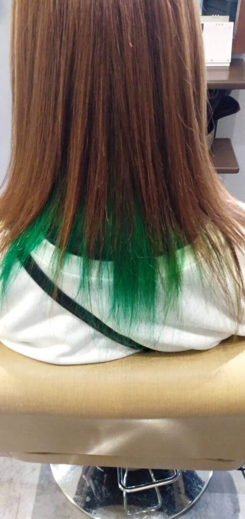 内側の髪を緑色に染めた若い女性